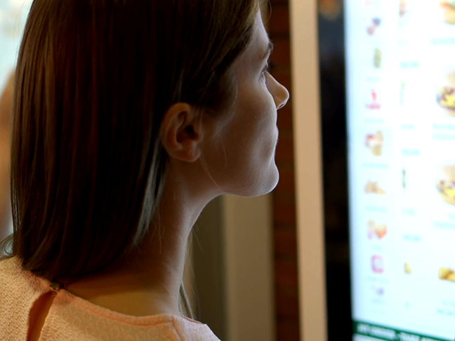 Gros plan sur une femme consultant un menu de commande automatique dans un restaurant à service rapide