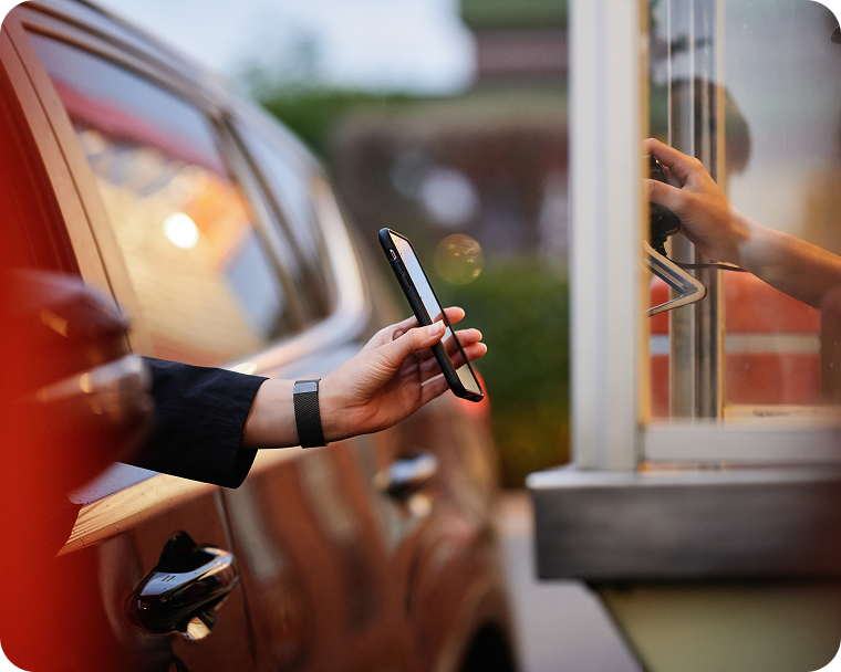 A quick service employee accepts a customer’s mobile payment in the drive thru.