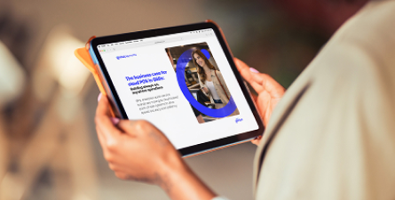 Person viewing a tablet with a white-and-blue report page featuring a headline and a woman’s photo.