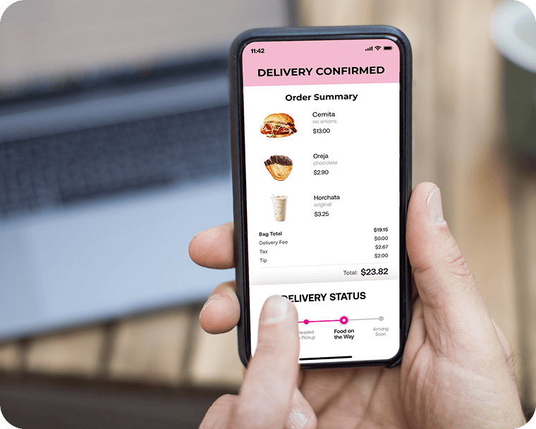 A person holds up a phone that displays the interface for a food ordering app on the screen.