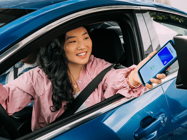 A person sits in a car while ordering food at a drive thru.