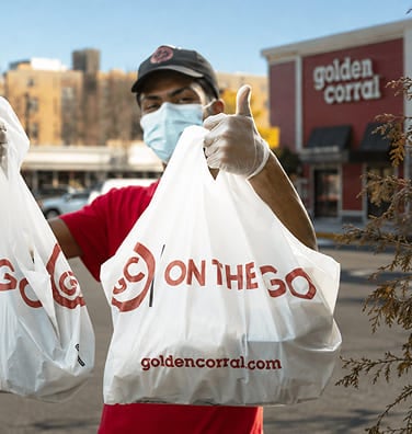 Delivery person wearing a mask holding Golden Corral takeout bags.