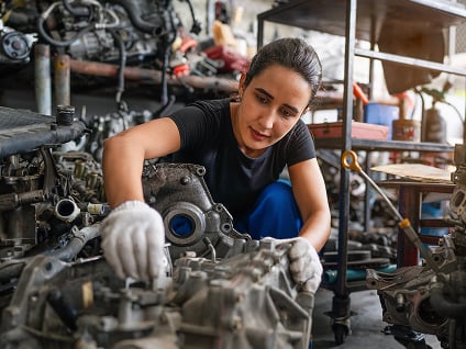 Un technicien en réparation automobile débranche le connecteur d'un ventilateur du radiateur d'une voiture.