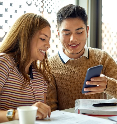 Two university students studying look at a mobile phone.