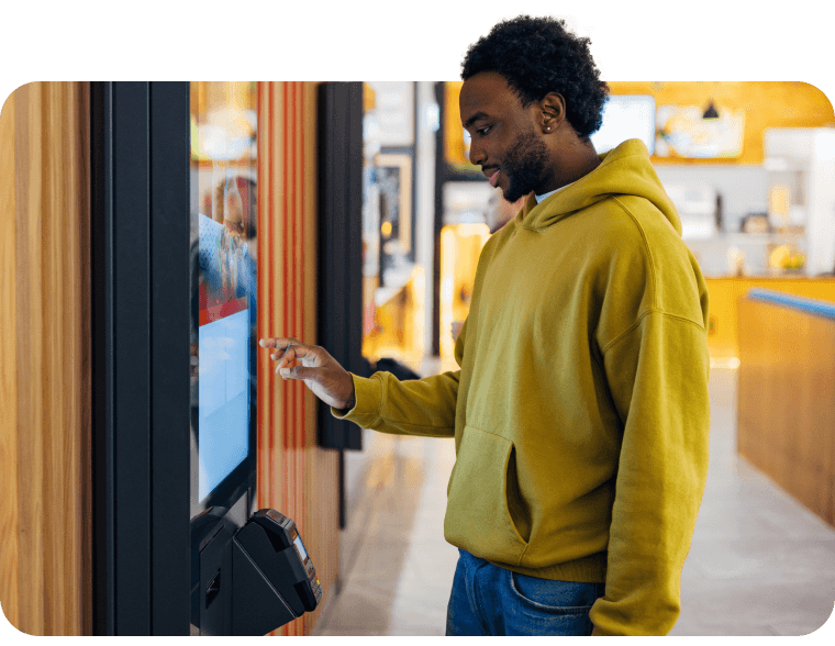 A college student makes a payment on a kiosk outside a university dining hall.