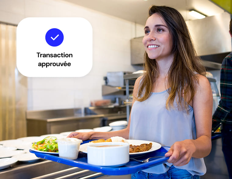 Après avoir effectué une transaction, une cliente de la cafétéria transporte un plateau de nourriture jusqu'à sa destination.