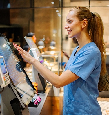 A healthcare worker makes a payment on a kiosk at a hospital cafeteria.