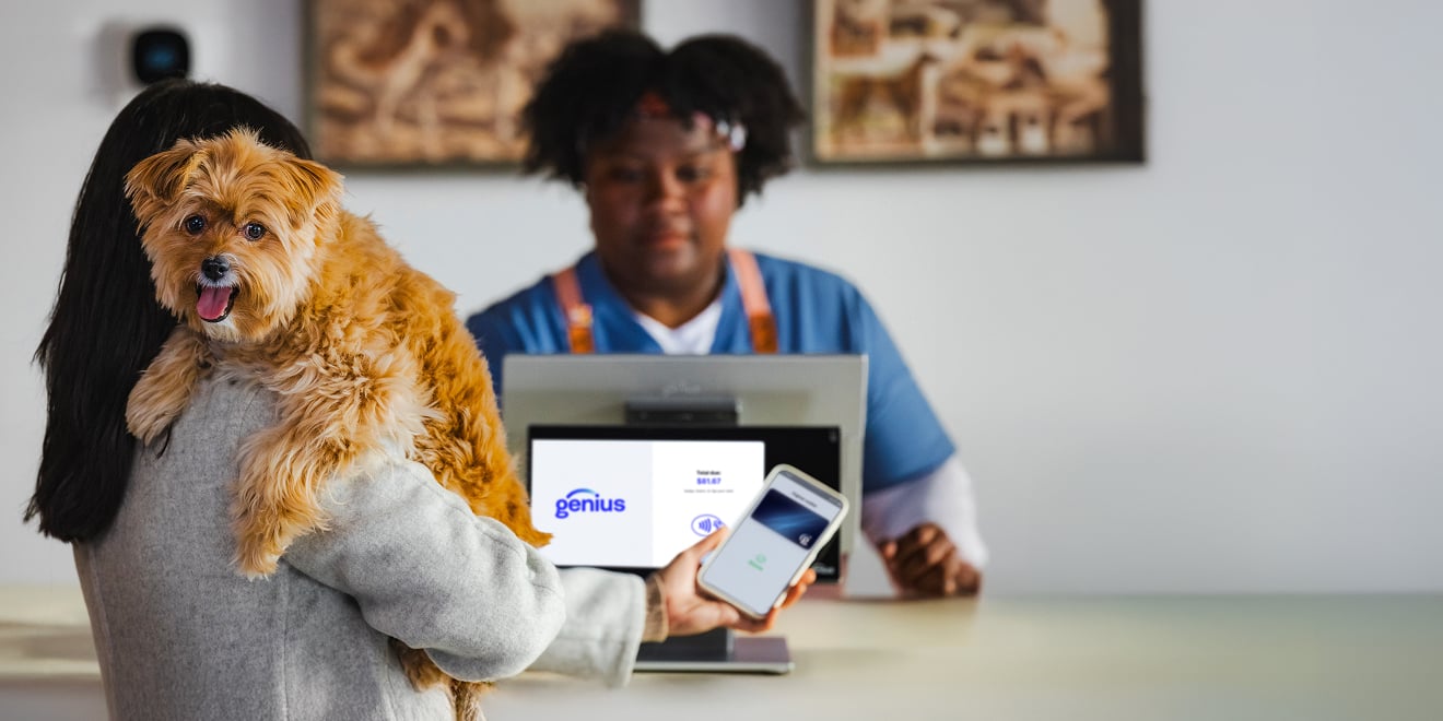 Customer holding her dog using a digital wallet to pay for grooming services on Genius customer-facing POS