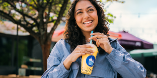 Drink shop customer smiling and holding a boba tea