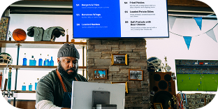 Restaurant employee behind bar standing in front of a Genius digital menu board and looking down at a Genius countertop POS