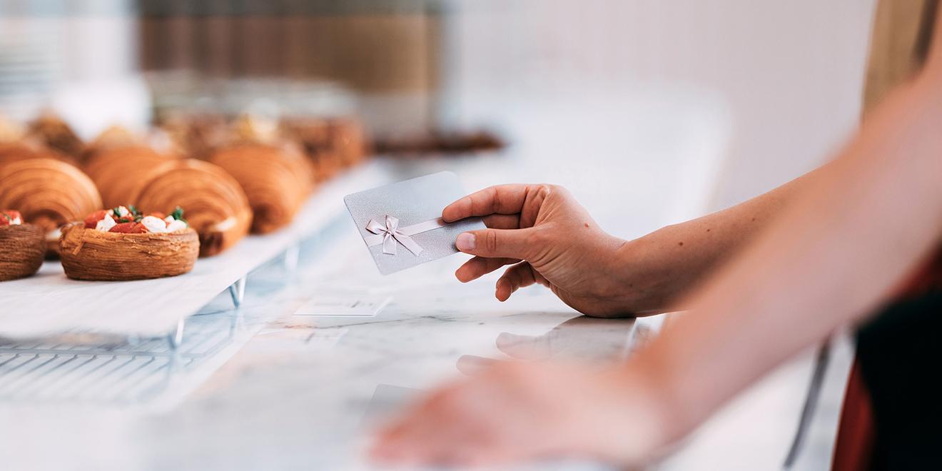 A customer holding a gift card at a bakery counter.
