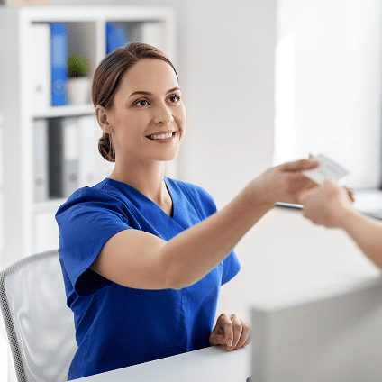 Healthcare employee at front desk taking card from patient