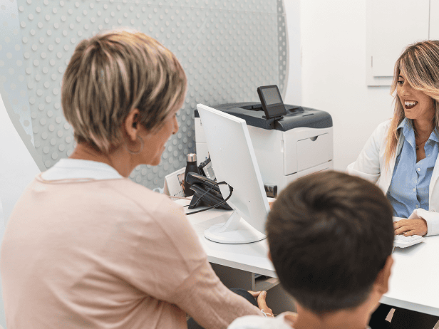 Medical employee talking to patient and her child at desk