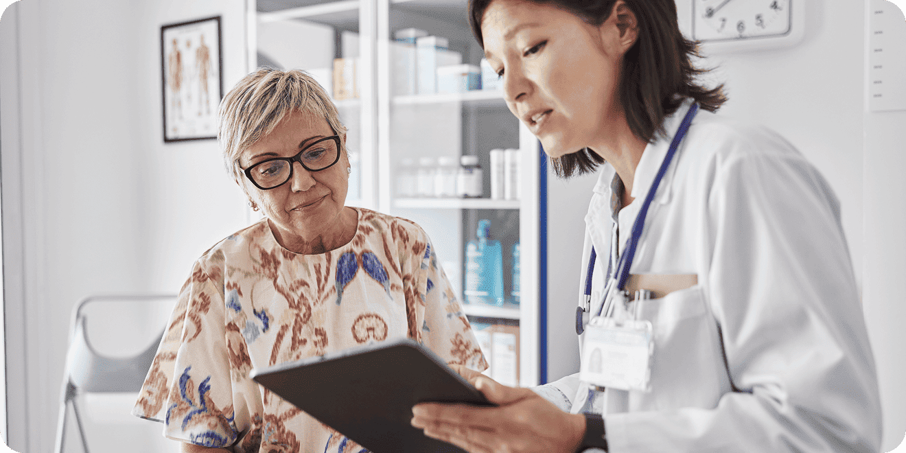 Doctor showing medical results on a tablet to a senior patient in a clinic.