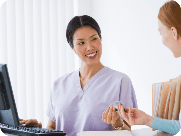 Healthcare employee talking to patient at desk and smiling