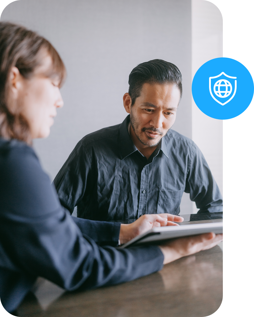Two people discuss payment security details while looking at information on a tablet. 