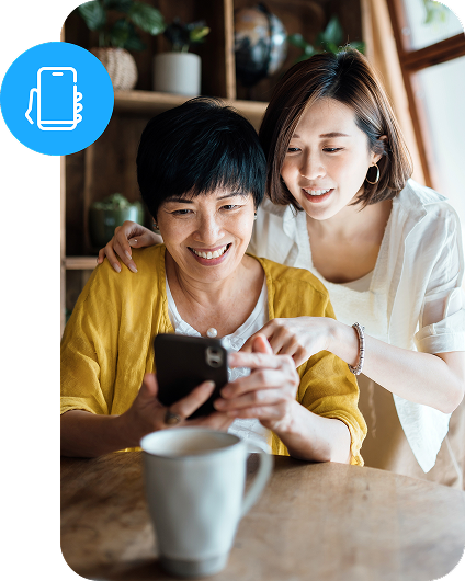 Two women smile while looking at a mobile phone together and a circle icon shows a phone in a hand.