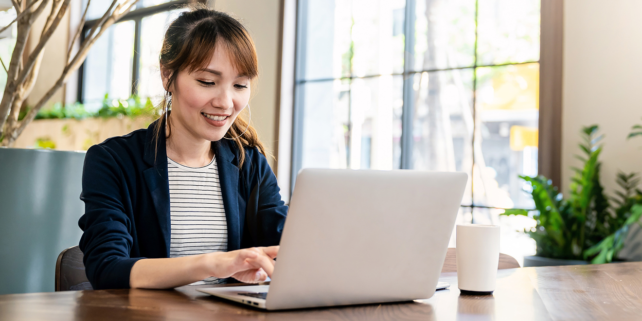 A business owner smiling while looking at her laptop in a coffee shop.