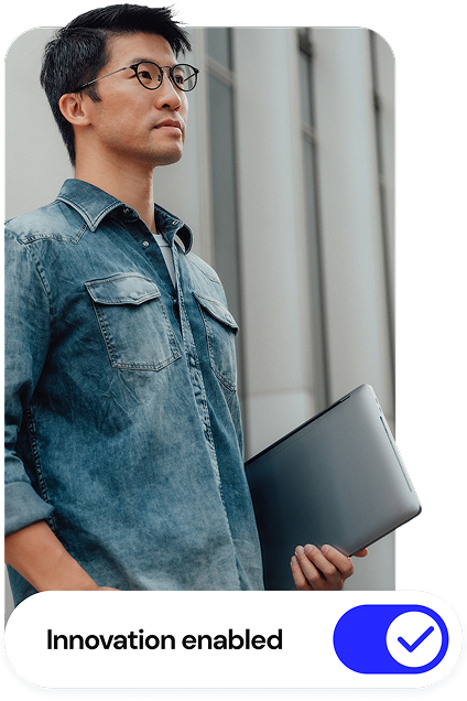 A man in a denim shirt holding a laptop.