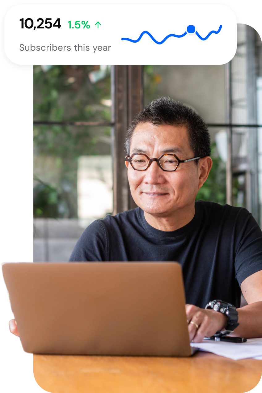 An image of a person sitting at a laptop with a soft UI callout that reads “Subscribers this year: 10,254.”