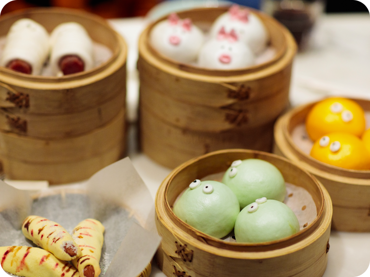 An image of several bamboo steamer baskets holding colorful bao buns.