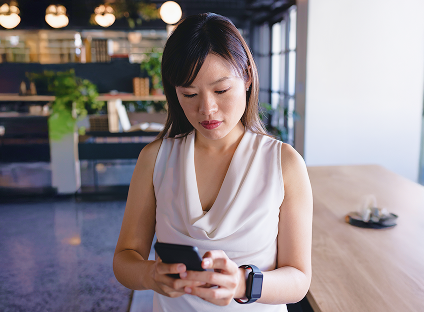 A woman sits in a swanky cafe using her smart phone.