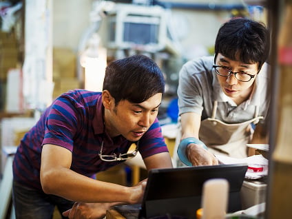 Two restaurant employees looking down at a laptop 