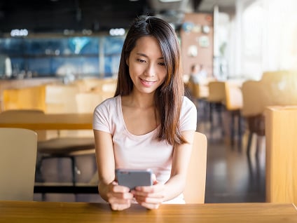 Smiling restaurant employee looking down at phone contacting POS support via WhatsApp