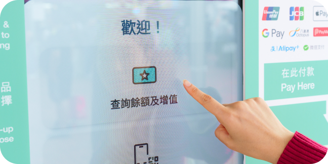 A hand points to a kiosk touch screen that shows event and venue information like ticketing and ways to pay.