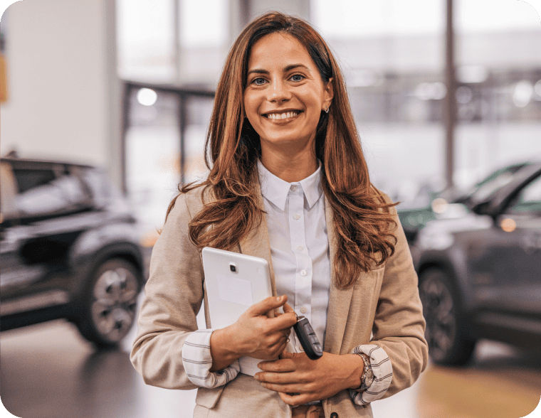 Car saleswoman smiling and holding a tablet and car keys