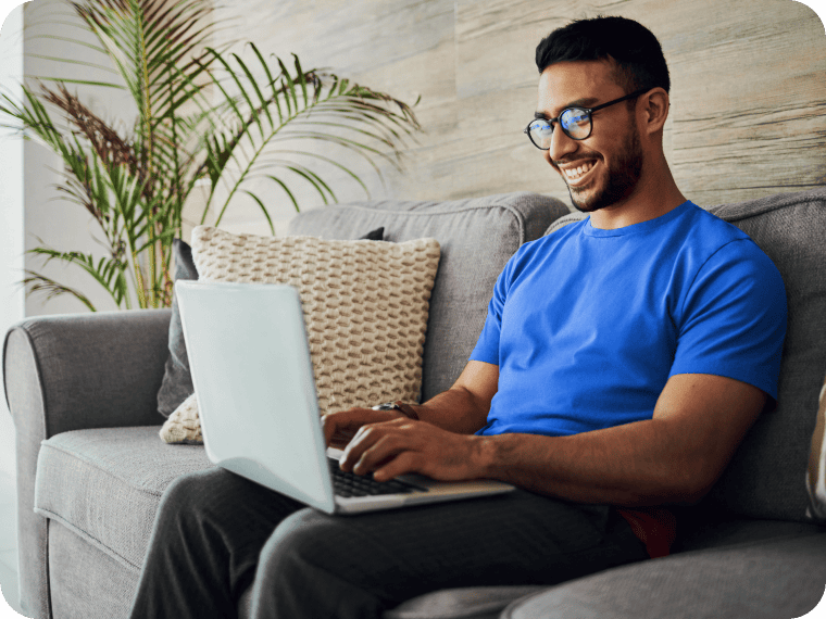 Smiling customer typing on a laptop on his couch