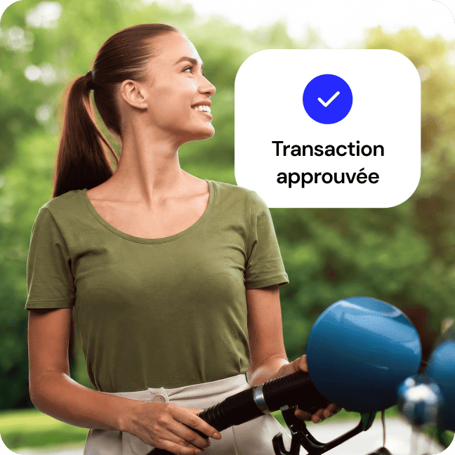 Femme souriante utilisant une pompe à carburant affichant le message « Transaction approuvée ».