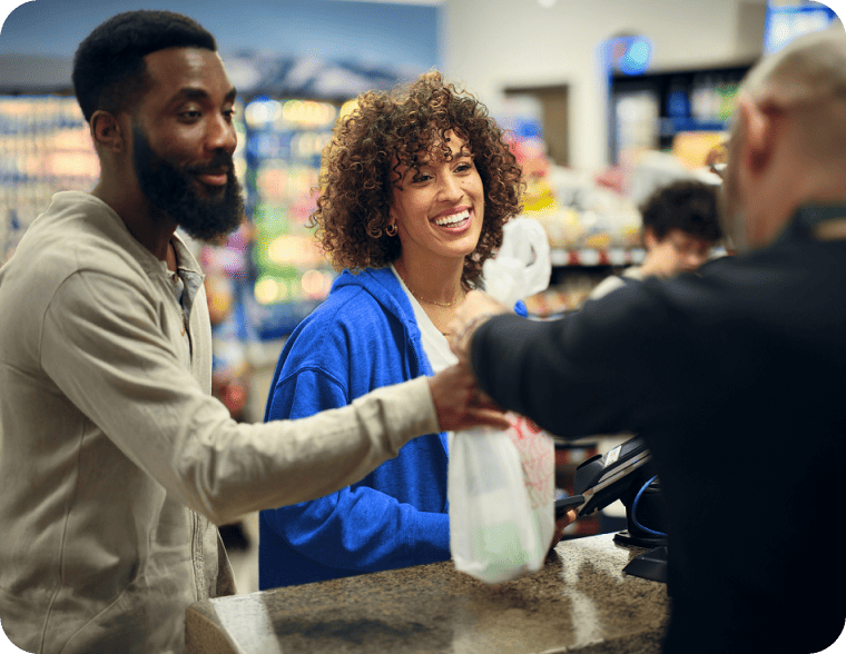 Smiling customers receiving their shopping bag at a store checkout.