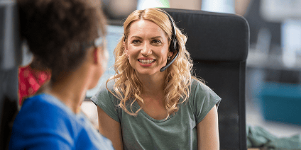 Un agent du service client portant un casque-micro sourit tout en collaborant avec un collègue.
