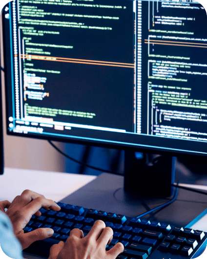 Des mains tapant sur un clavier mécanique devant un écran affichant du code.