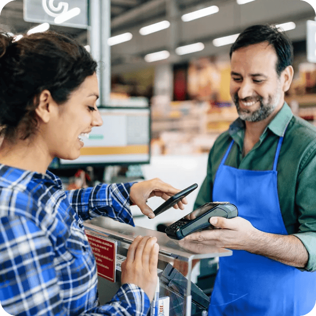 Une femme effectue un paiement via un portefeuille mobile à la caisse d'un supermarché.