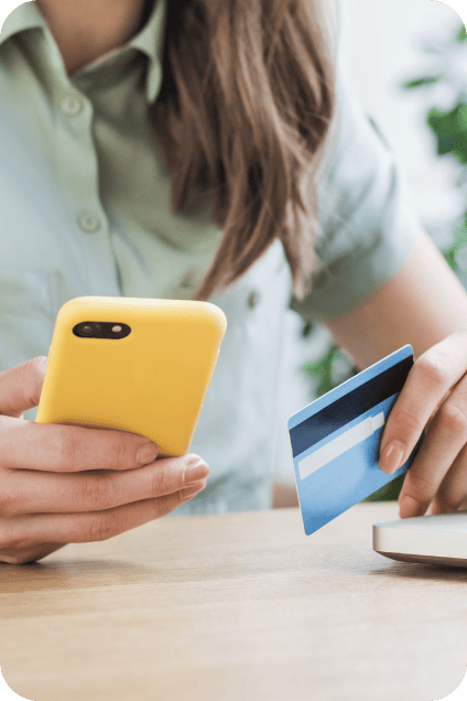 A closeup of one hand holding a mobile phone and the other holding a payment card.