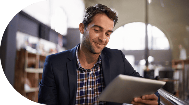 Un homme sourit pensivement en lisant des informations sur une tablette.