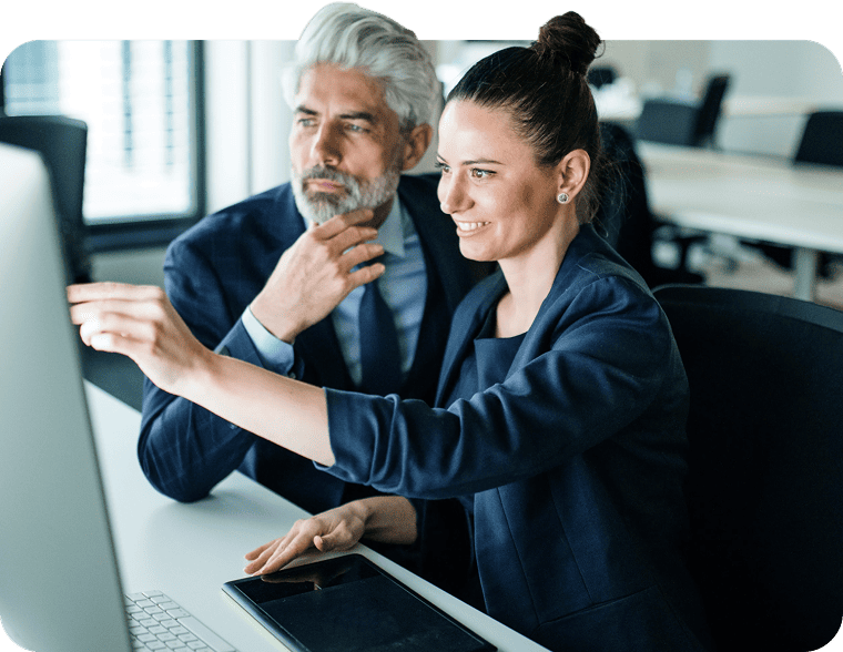 Woman pointing at a computer screen while collaborating with a colleague.