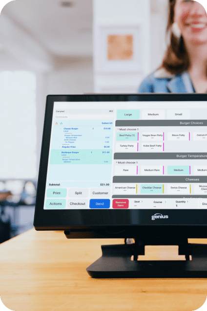 Point-of-sale touch screen showing a food order menu with a smiling staff member behind.