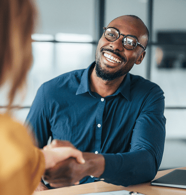 Smiling businessman shaking hands at a desk.