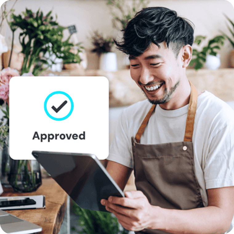 Plant store employee smiling while looking down at a mobile POS. A popup window shows an “Approved” transaction.