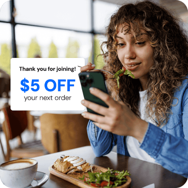 Restaurant customer signing up for a loyalty program on her phone while dining in. A popup screen reads “Thank you for joining! $5 OFF your next order”
