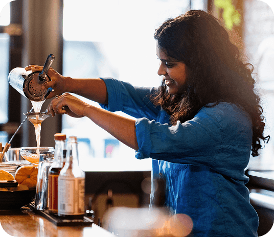 Bartender pouring a drink out of a shaker into a glass
