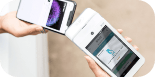 Customer tapping a smartphone on a white handheld POS terminal to pay.