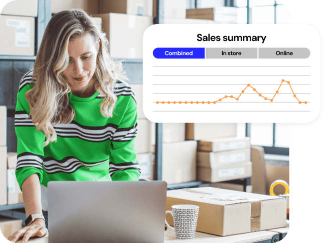 Propriétaire d'une petite entreprise dans une salle de stock souriant à son ordinateur portable. Un écran «Résumé des ventes» avec un graphique de vente sort.