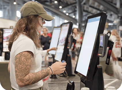 Event guest stands in front of self-order kiosk in the concourse of a venue