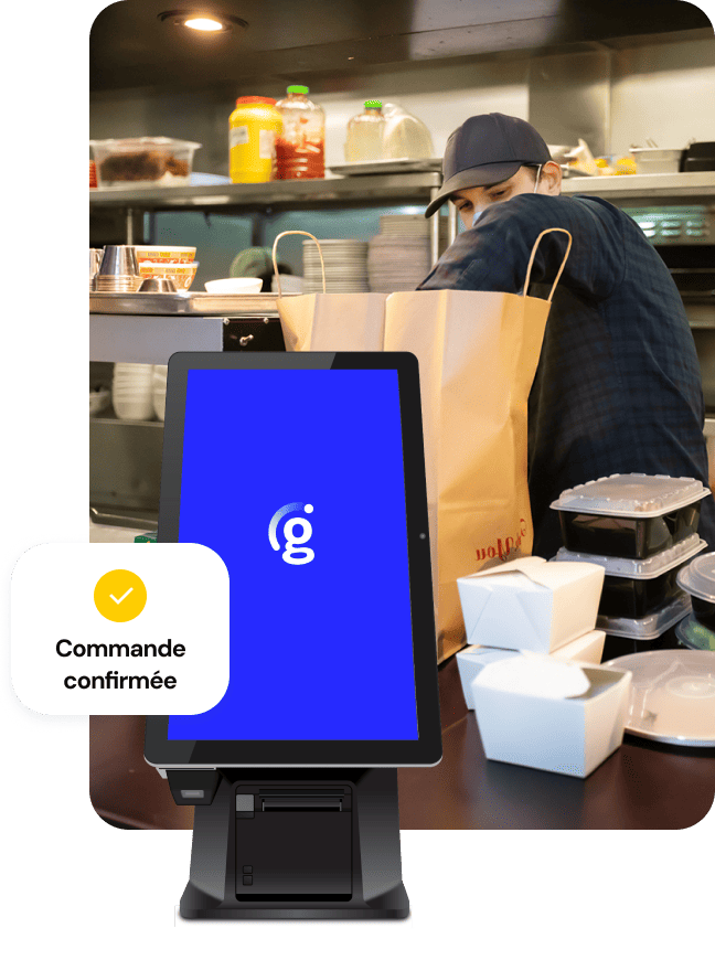 Vue d'une cuisine animée où une personne empile des contenants à emporter dans un grand sac en papier brun ; une borne Genius avec un petit message d'interface utilisateur indiquant « Commande confirmée » se trouve au premier plan.