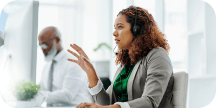 Close-up of a female call center employee wearing a headset and talking in a modern office space.