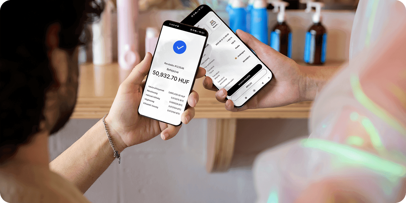 Közeli felvétel két okostelefonról, amelyek két személy közötti digitális mobiltranzakciót igazolnak.